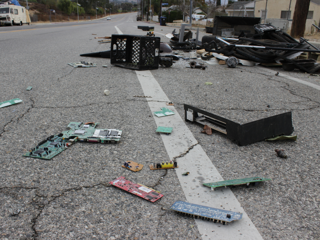 various computer parts and garbaged dumped on a roadway