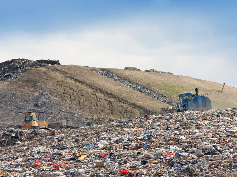Workers moving waste in a landfill