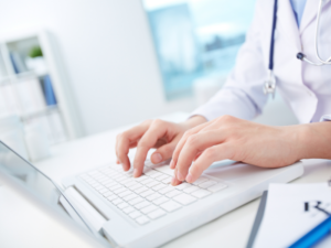 A female doctor typing sensitive patient information into a laptop